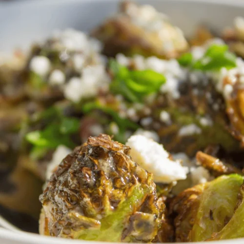 A plate of Roasted Brussels Sprouts Variations sprinkled with parmesan cheese, ready to serve.